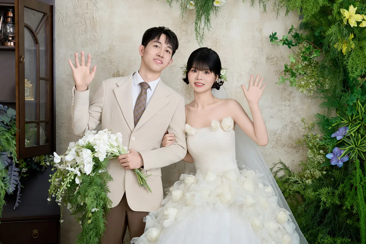 手持花束向镜 头挥手的新郎与新娘